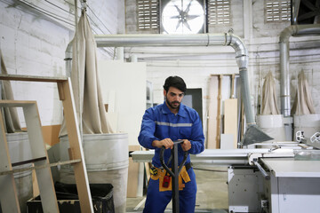 Fototapeta premium Worker in blue uniform using tools in woodshop during daytime