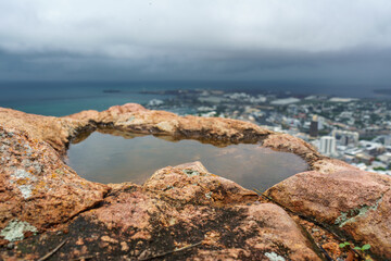 Closeup of a puddle in rocks with a stormy scenic background