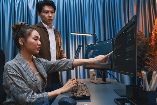 IT developers discussing with point to intelligent website development coder system running data online two screens information technology at neon light room at modern office. Infobahn.