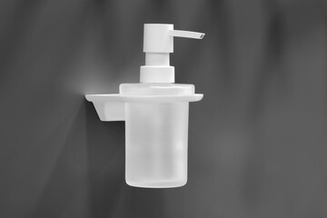 A white soap dispenser with a clear container is mounted on a wall. The dispenser is designed to hold liquid soap and the container is made of clear plastic. The dispenser is easy to use