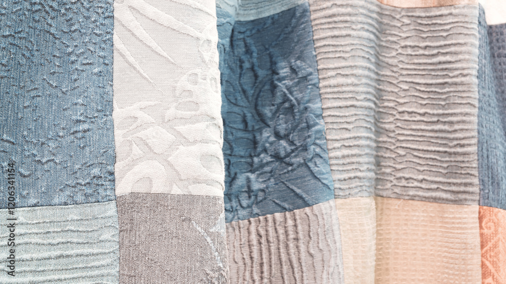 Poster A collection of different colored fabric pieces are displayed in a row. The colors include blue, gray, and white. The arrangement of the pieces creates a sense of texture and depth
