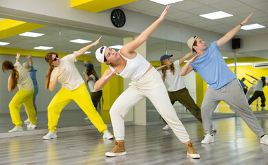 Obraz premium Cool sportive teenagers in casual wear practicing new moves during dance training together in studio