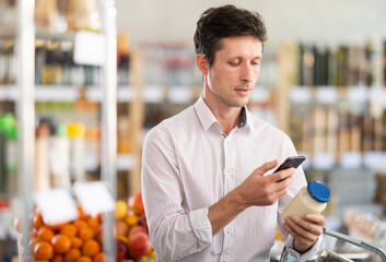 Adult man buyer scanning qr code for mayonnaise sauce in grocery store