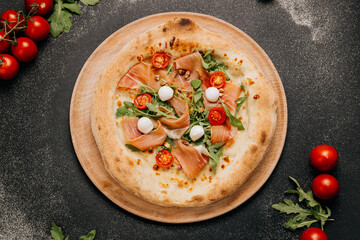Gourmet pizza with prosciutto, mozzarella, arugula, and cherry tomatoes, food lover's feast