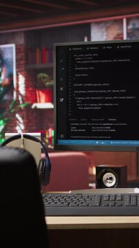 Vertical video Development console visible on computer screen in modern apartment workspace. Software tools and lines of code displayed on PC monitor in home living room, technology concept