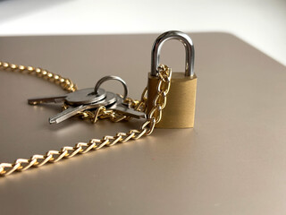 Golden chain and brass padlock with keys on brown surface: security and protection concept