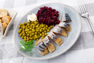 Cold smoked mackerel with grated beetroot and green peas served in a plate with other table appointments