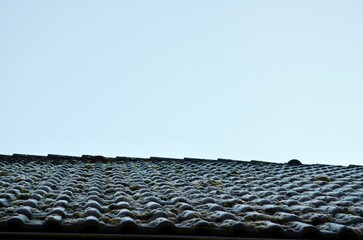 tiled roof covered in snow in winter with icicles hanging