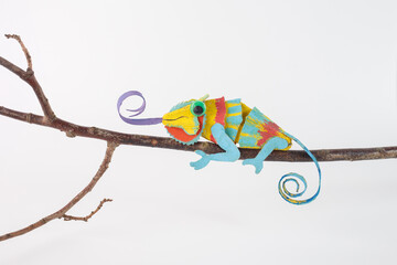 Recycled cardboard chameleon on branch with vibrant colors and curled tongue, eco-friendly craft for sustainable projects, creative recycling and educational design © Elena