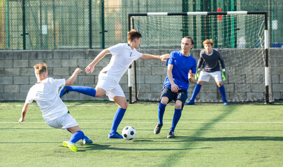 Football soccer players with ball. Footballers kicking football match on the pitch. Young teen soccer game