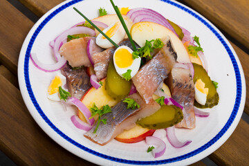 Marinated herring with sliced apples, cucumbers, onion - traditional dish of Norwegian cuisine