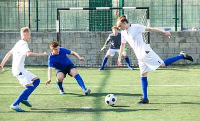 Youth football player kicking ball in direction of goal
