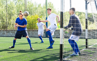 Youthful football players challenging for ball in goalmouth zone