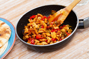 Appetizing chicken fajitas with peppers and onion served in fry pan with tortillas. Mexican cuisine
