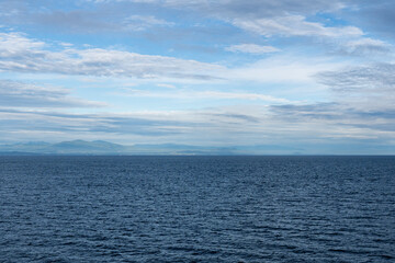 clouds over Strait of Georgia blue sky water landscape mountains on the horizon British Columbia Canada