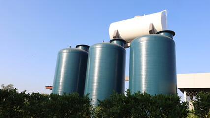 Three plastic water storage tanks. Dark green fiberglass water storage tanks outdoor for water storage on white water tank background and sky low angle with copy space. Selective focus