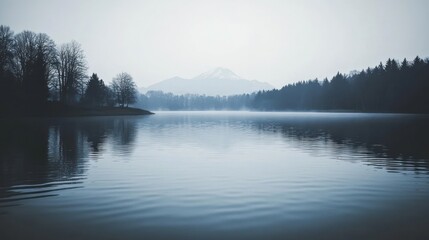Serene lake reflecting misty mountains and trees.