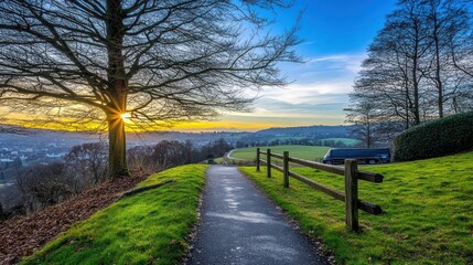 Fototapeta premium Scenic sunset view over valley, path, and trees.