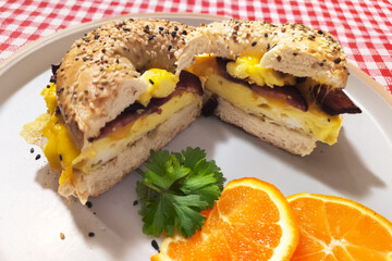 Breakfast bagel on plate with orange slices and garnish