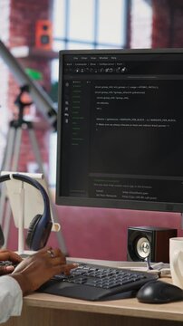 Vertical video Developer at computer desk coding while listening music, creating software, implementing algorithms. Remote worker with headphones on at home working with code editor, building