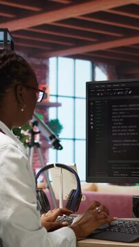 Vertical video Developer at computer desk coding while listening music, creating software, implementing algorithms. Remote worker with headphones on at home working with code editor, building