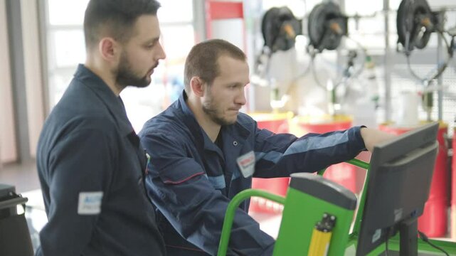 Auto Mechanics Performing Vehicle Diagnostics on Computer