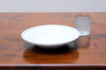 Empty dining plate and drink glass on wooden table