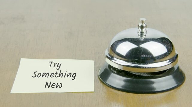 Finger Index Ringing Bell with Try Something New Text or Word on Yellow Note Paper on Desk or Table