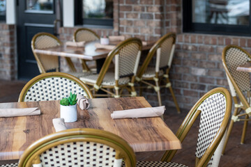 The exterior seating area of an empty restaurant or bistro. The tables are in rows with rattan...
