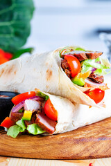 Doner kebab, shawarma on round wooden board, vegetables, herbs, spice grinder, modern classic white kitchen