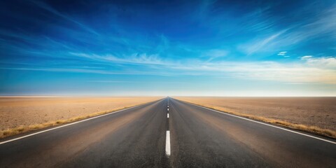 Naklejka premium Endless Asphalt Road Stretching Towards a Hazy Horizon Under a Vast Blue Sky