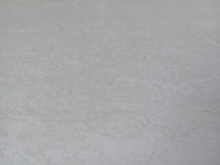 Subtle texture of a light-colored ceramic floor tile, featuring a soft and irregular pattern. Its surface appears smooth with a matte finish, creating a neutral and minimalistic aesthetic.