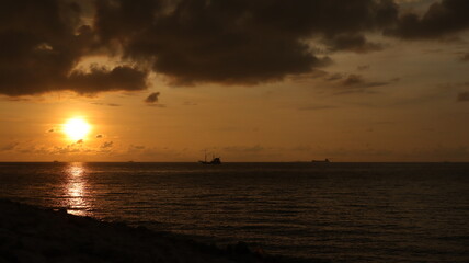 Low orange sunset in dramatic clouds over ocean in Indonesia