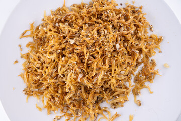Crispy Golden Fried Anchovies on White Plate. A tantalizing close-up of crispy golden fried anchovies piled high on a pristine white plate against a minimalist white backdrop.