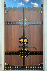 A Chinese-style wooden gate with gold accents and lion door knockers, featuring traditional...