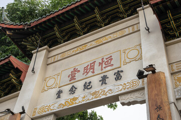 A traditional Chinese temple gate adorned with intricate calligraphy and golden dragon motifs. The...