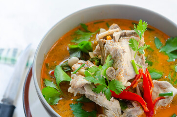 Spicy pork bone soup in a bowl with red chili and fresh herbs, perfect for Asian cuisine.