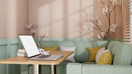 A laptop placed on a wooden table in modern pastel cafe or office lounge.