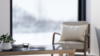 A close-up of a minimalist coffee table and an armchair by the window in a cozy simple room.