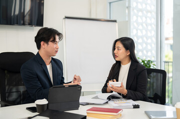 Two smart and professional Asian businesspeople are meeting in a meeting room, planning a project.
