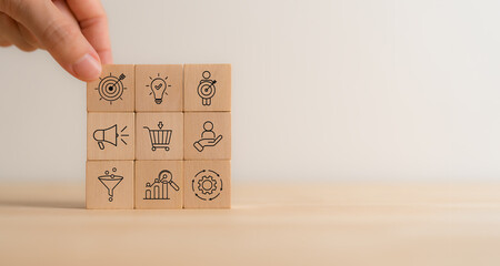 Marketing and business strategy, goals and achievement concept. Wooden blocks featuring icons related to marketing, business strategies, customer targeting and analytics. Marketing management.