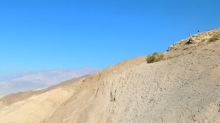Hiker on desert mountain ridge, panoramic valley view, sunny day, travel adventure