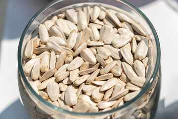 close-up photo of sunflower seeds with their white shells on the glass plate and on a white background