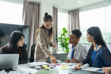 Group of Asian people using sticky notes on meeting table, brainstorming idea in modern office