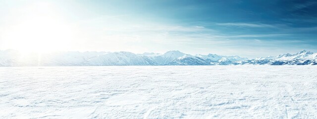 Fototapeta premium Breathtaking winter landscape with a vast, snow-covered field and majestic mountain range under a clear blue sky