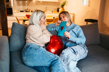 Obraz premium Women couple celebrating valentine's day exchanging gifts and love letters at home