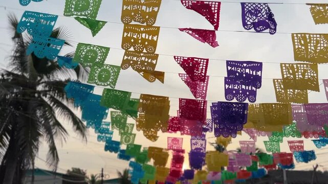 Brightly colored papel picado (perforated paper), a traditional Mexican decorative craft, flutter in the morning sunrise, with the name of the beach town Zipolite showing in some, in Oaxaca, Mexico.