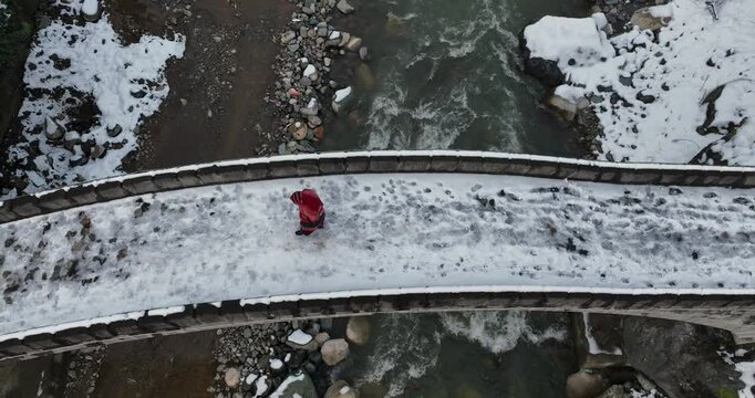 woman in a red dress walking on a stone bridge