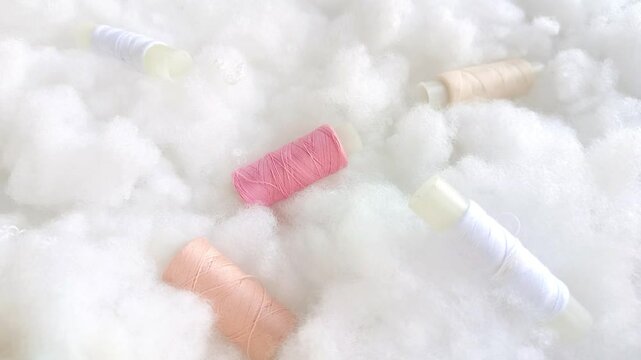 Coils with pink, beige and white threads on airy soft clouds, sintepon, cotton wool. Sewing production, atelier.
