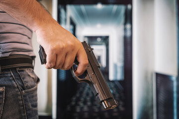 an armed criminal with a dhrt pistol enters the premises. Attempted robbery. Crime concept. bank robbery. self-defense with firearms. the man hides the gun behind his back.